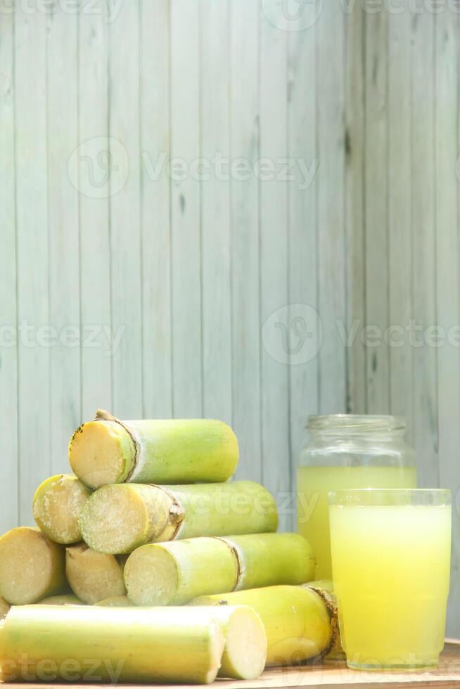 A pile of sugar cane with a glass of juice photo