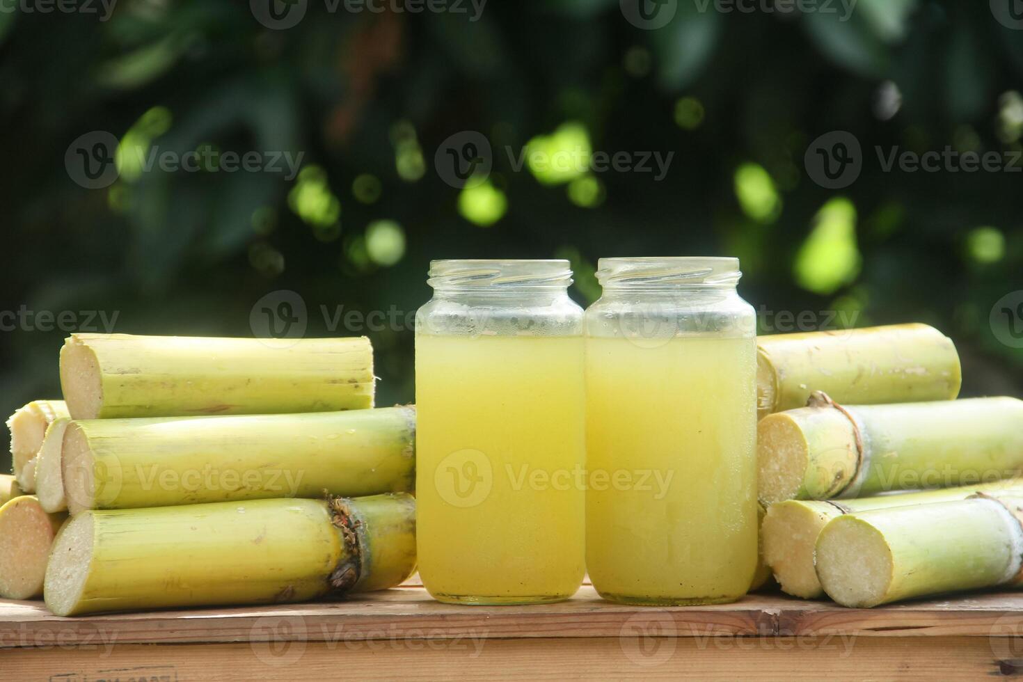 Two jars of sugar cane juice sitting on top of some sticks photo