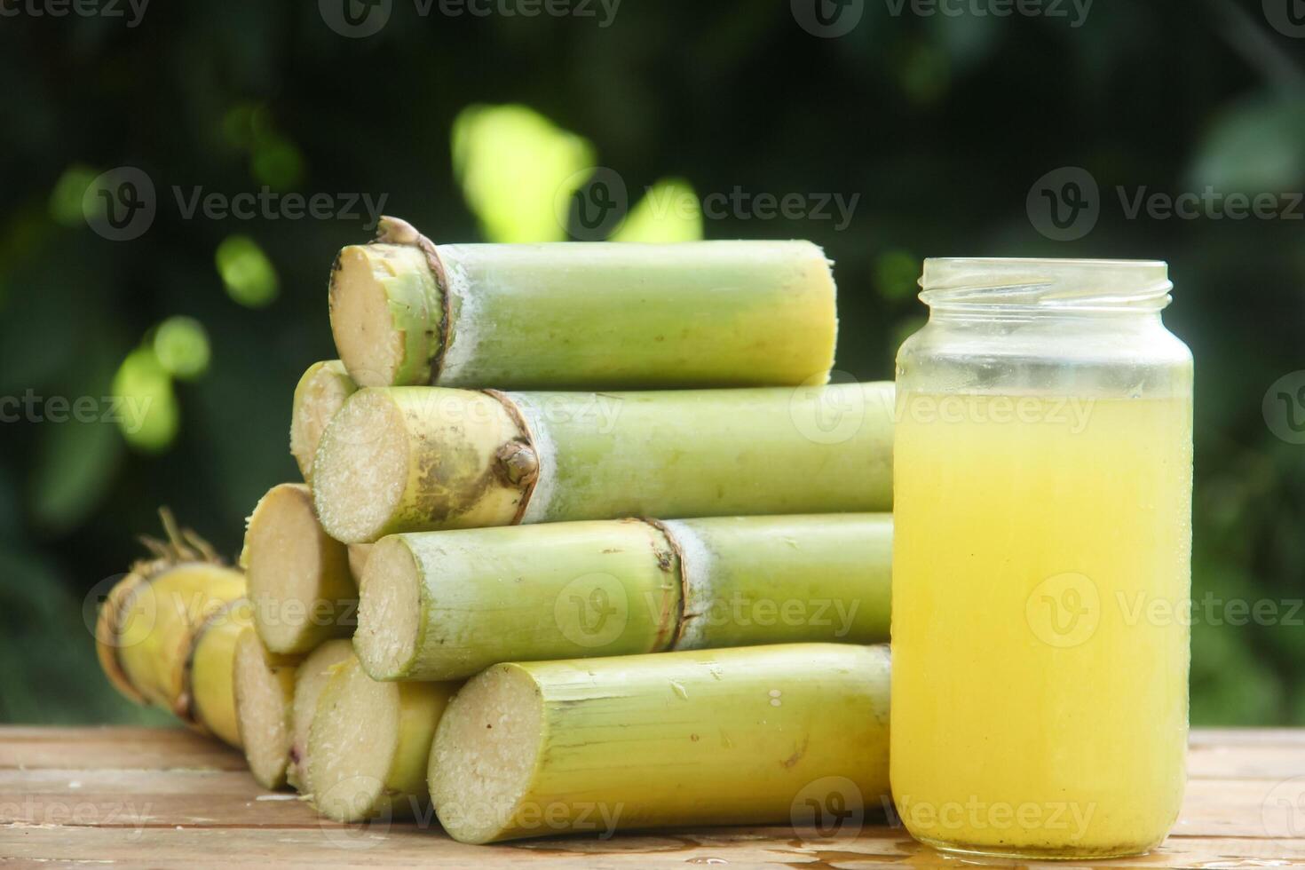 A jar of lemonade next to a stack of sugar cane photo