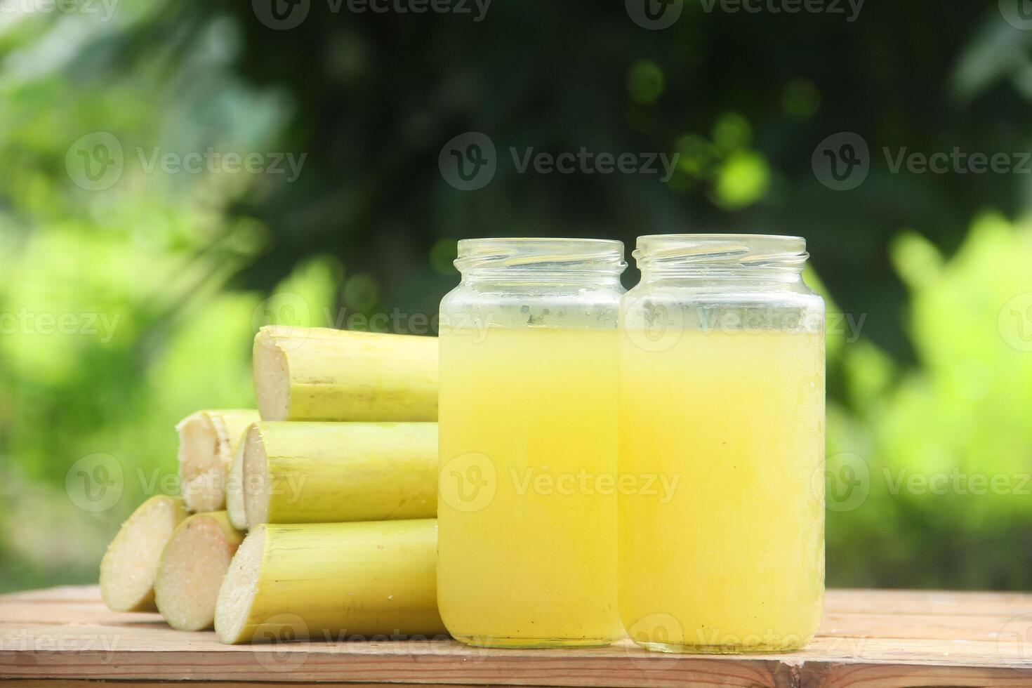 Two glass jars with yellow liquid sitting on a wooden table photo