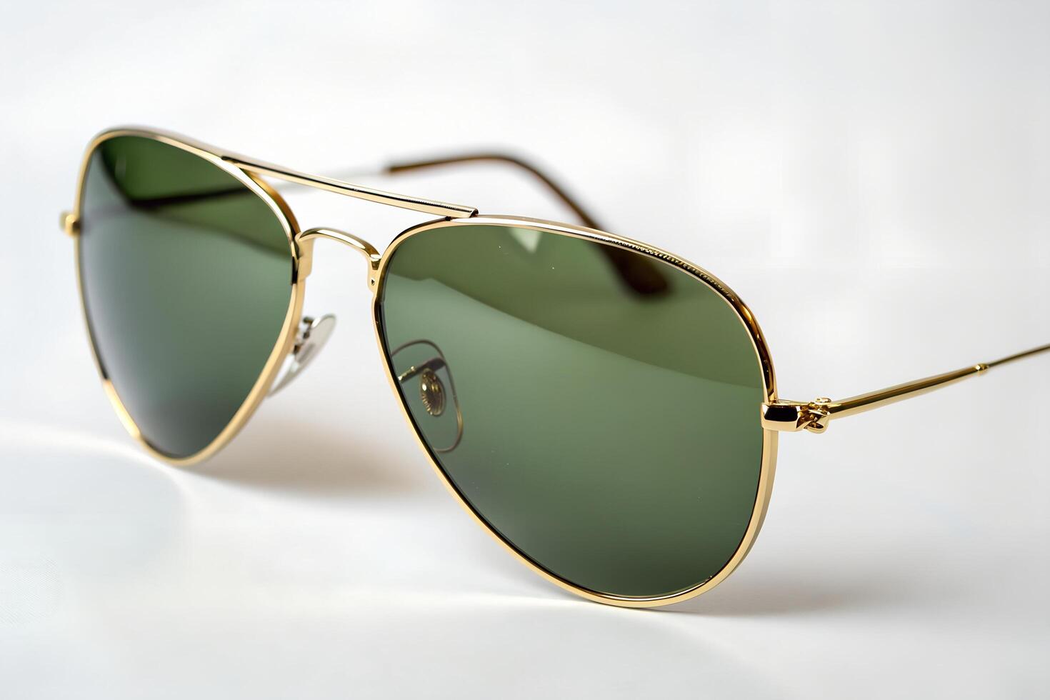 Classic aviator sunglasses with gold frames and green lenses rest stylishly against a white background photo