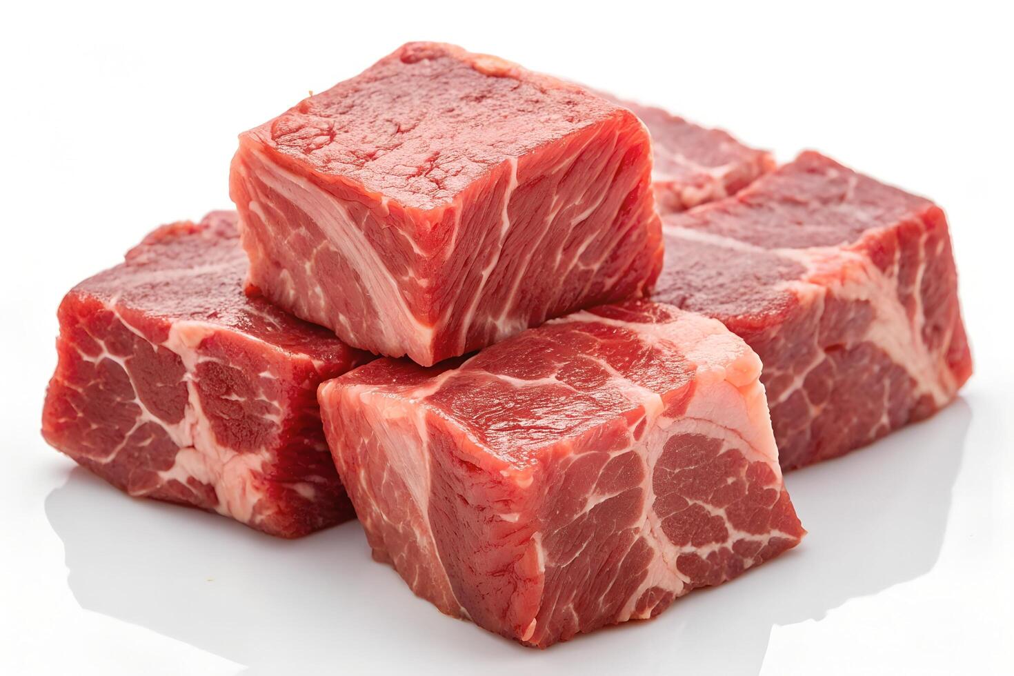 Close up reveals four fresh beef cubes with fat marbling on the white surface photo