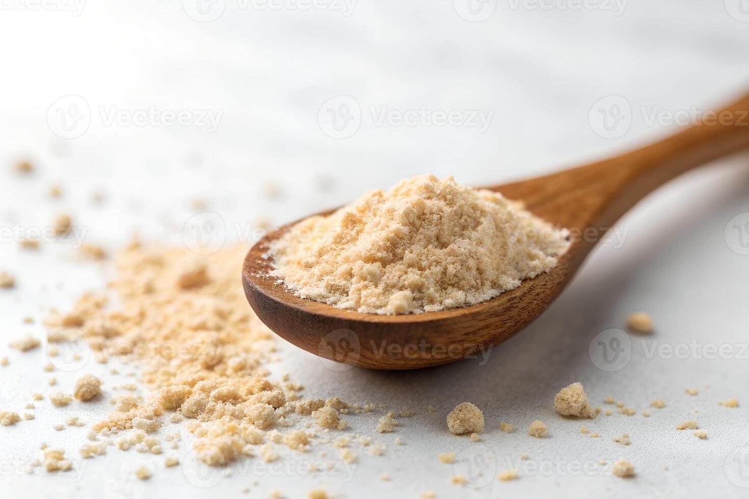 Closeup shows maca powder in wooden spoon and spilled out onto surface photo