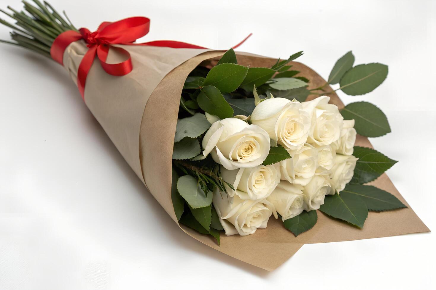Elegant bouquet features white roses wrapped in brown paper with a vibrant red ribbon photo