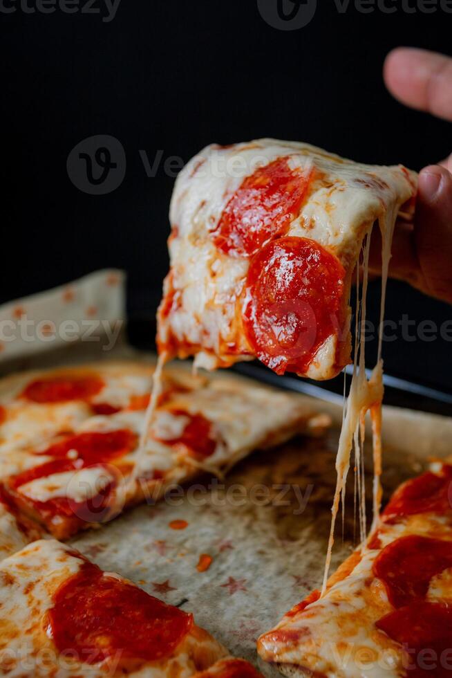 a person is holding a slice of pizza photo