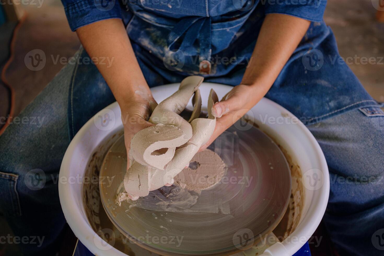 A person is making a pottery on a pottery wheel photo