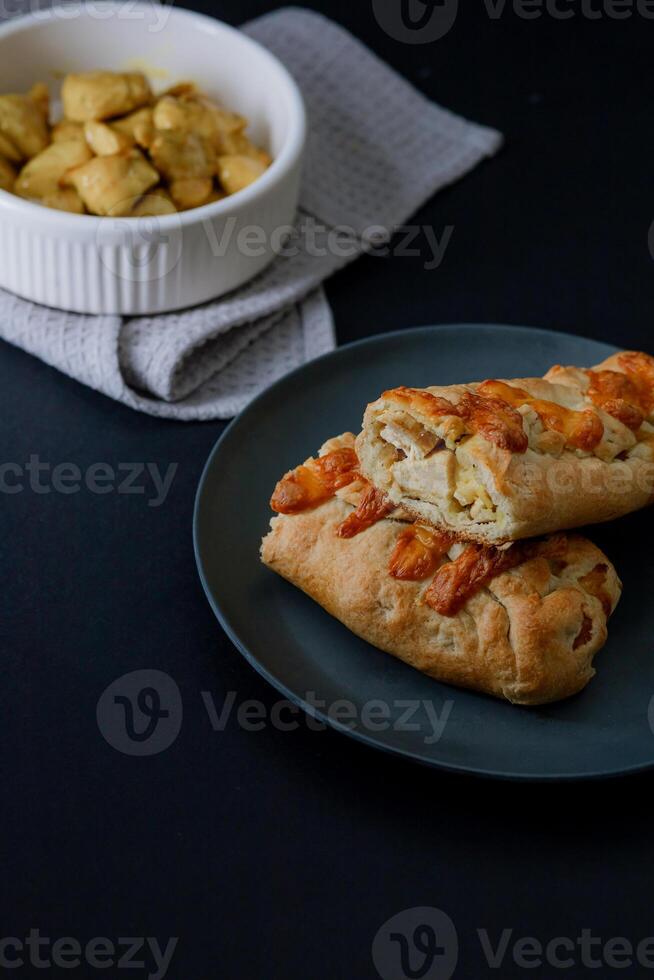 Gourmet chiken bake in dark food style, highlighting its golden crust and creamy filling in a sophisticated presentation. photo