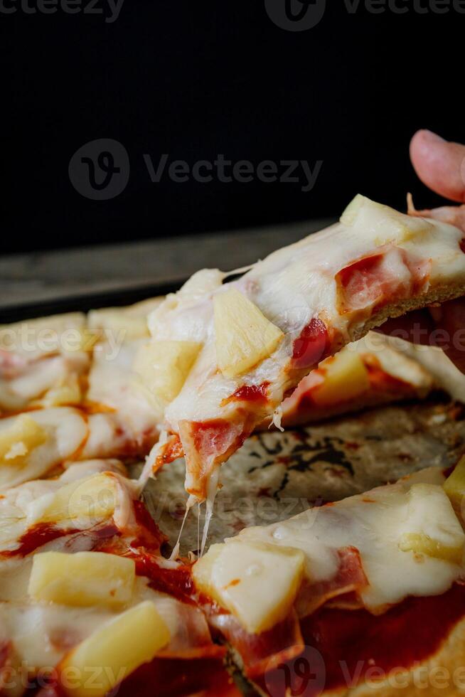 a person is taking a slice of pizza out of a pan photo