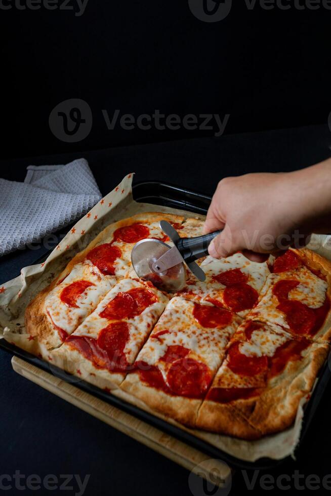 a person is cutting a pizza with a knife photo