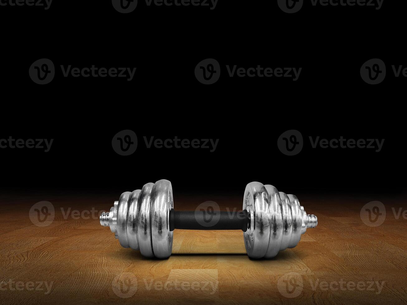 Silver dumbbells placed on a wooden floor, black background. photo