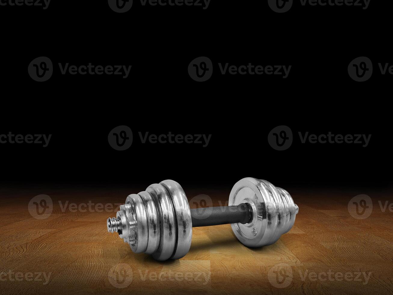 Side view of silver dumbbells placed on wooden floor, black background. photo