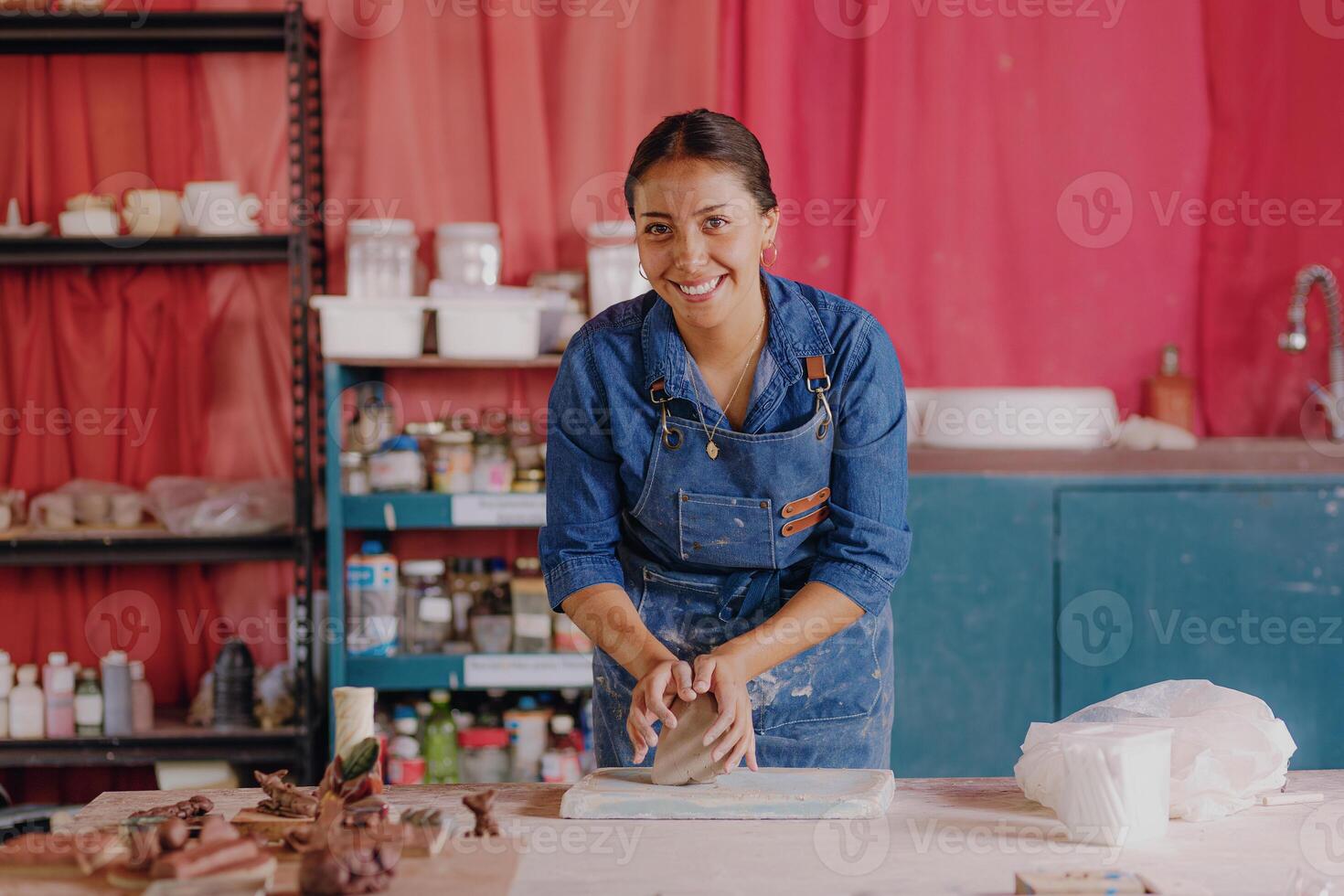 a woman in an apron is making clay pots photo