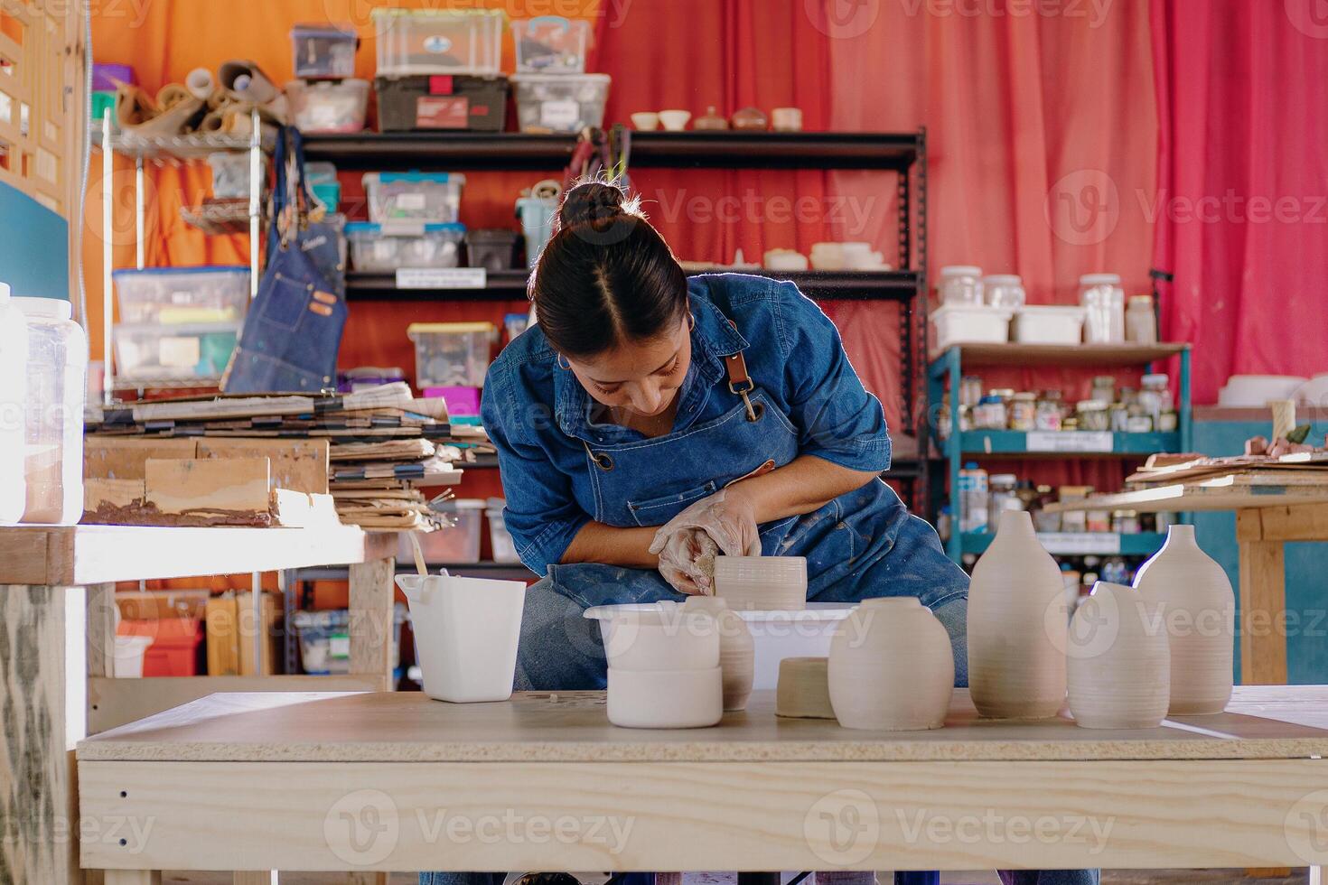 a woman is working on a pottery project photo