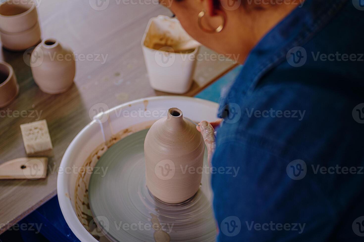 A woman is making a pot on a pottery wheel photo