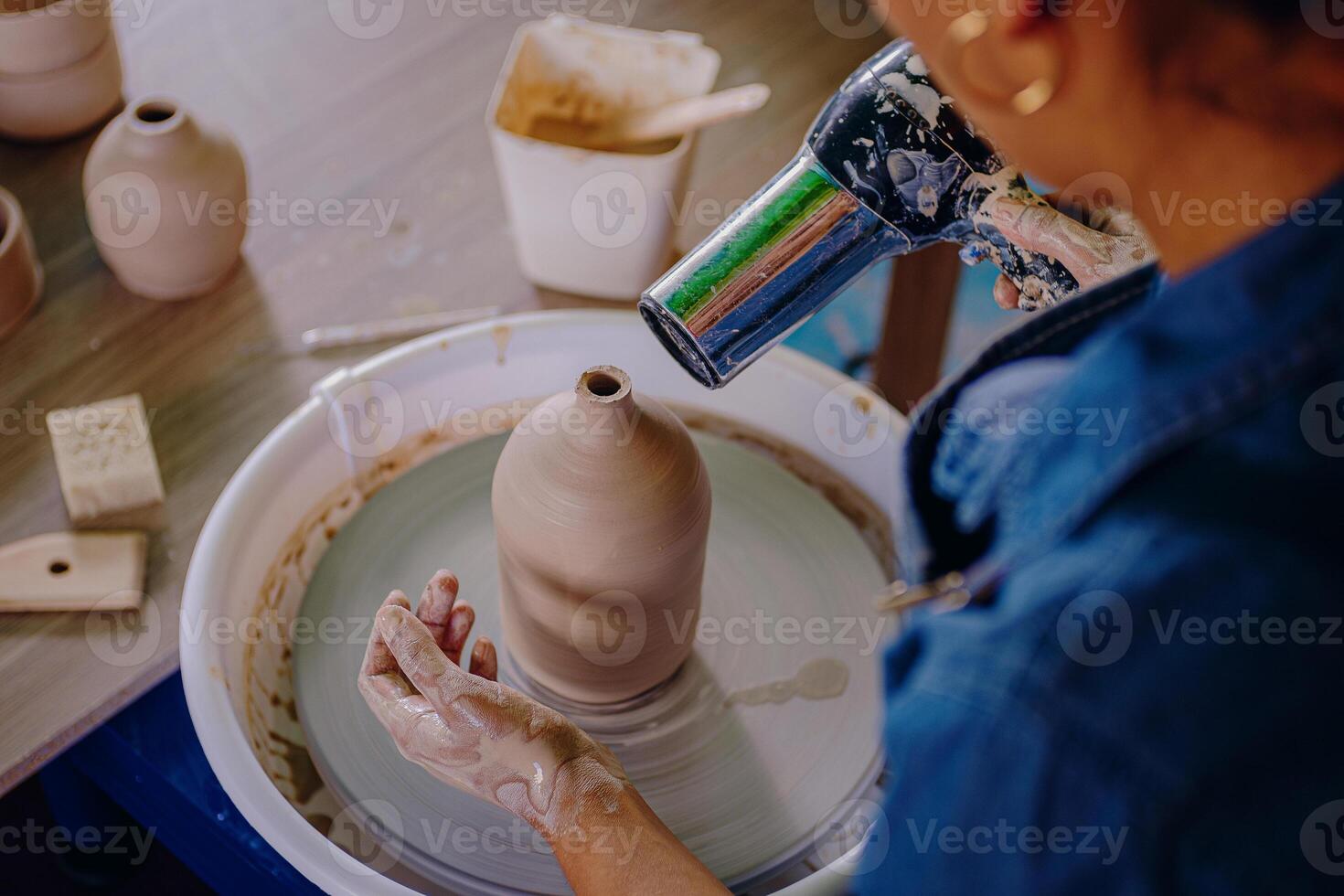 A woman is making a pot on a potter's wheel photo