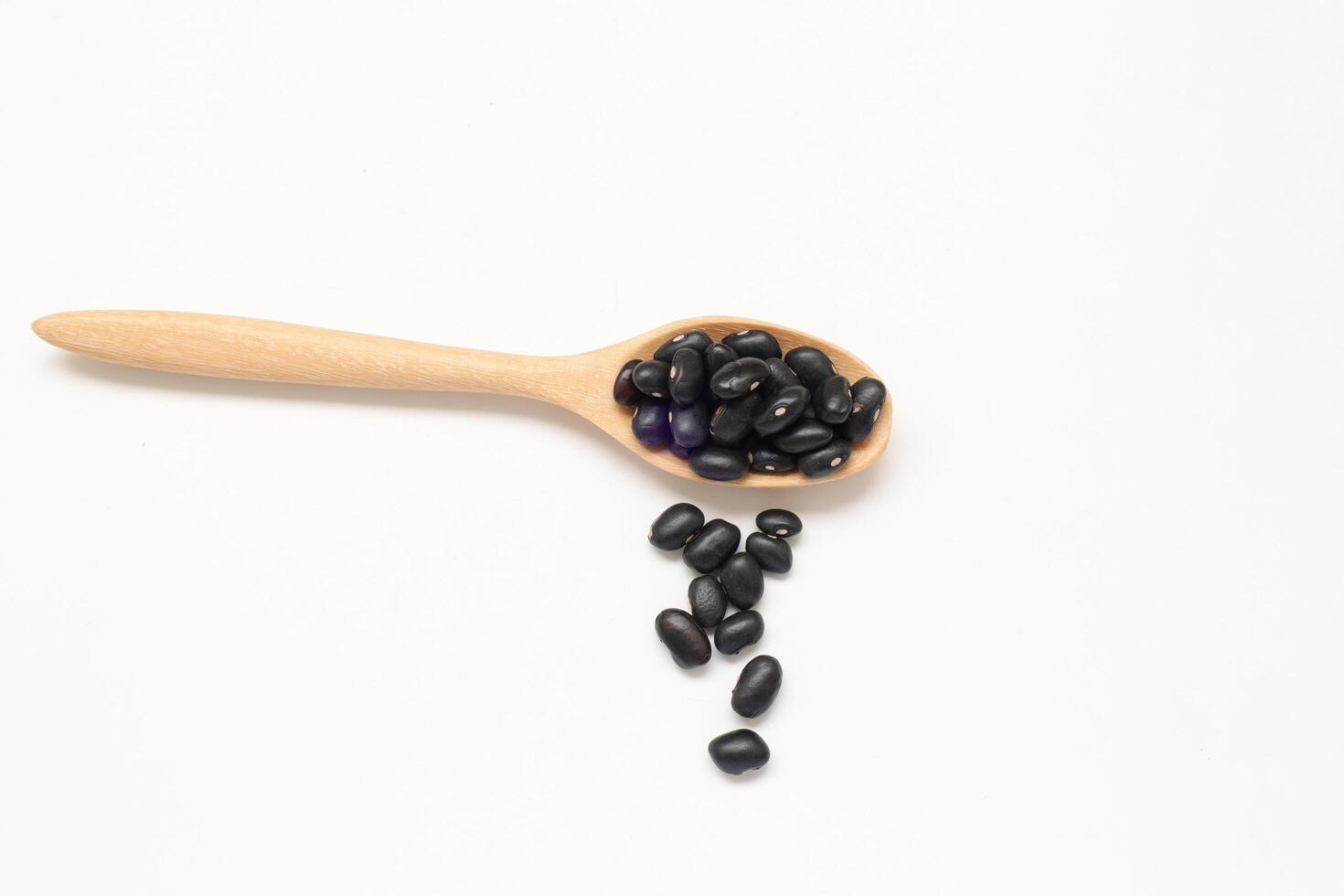 Black beans in spoon on white background photo