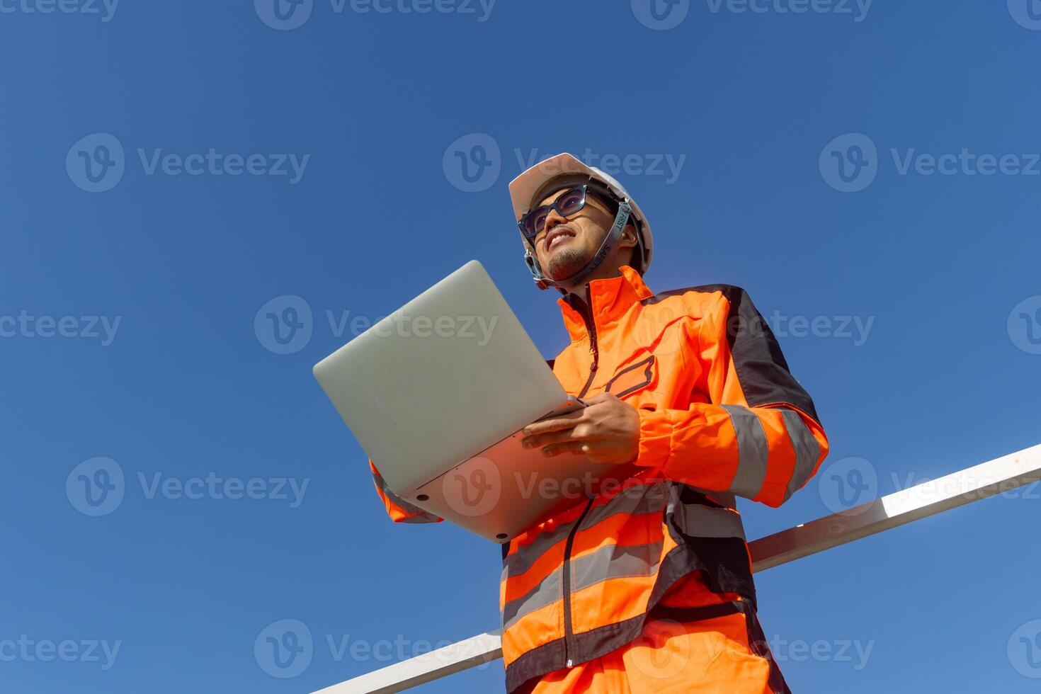 Asian engineer advance technology technician mechanic male standing with laptop computer on blue sky photo
