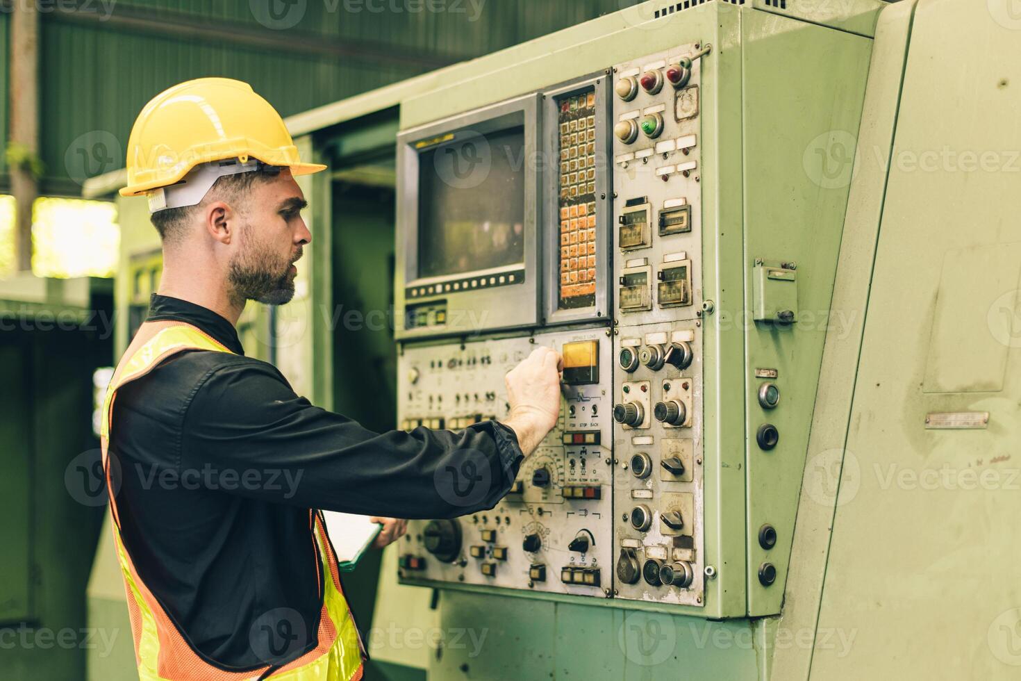A man in a hard hat and safety vest working on a machine photo