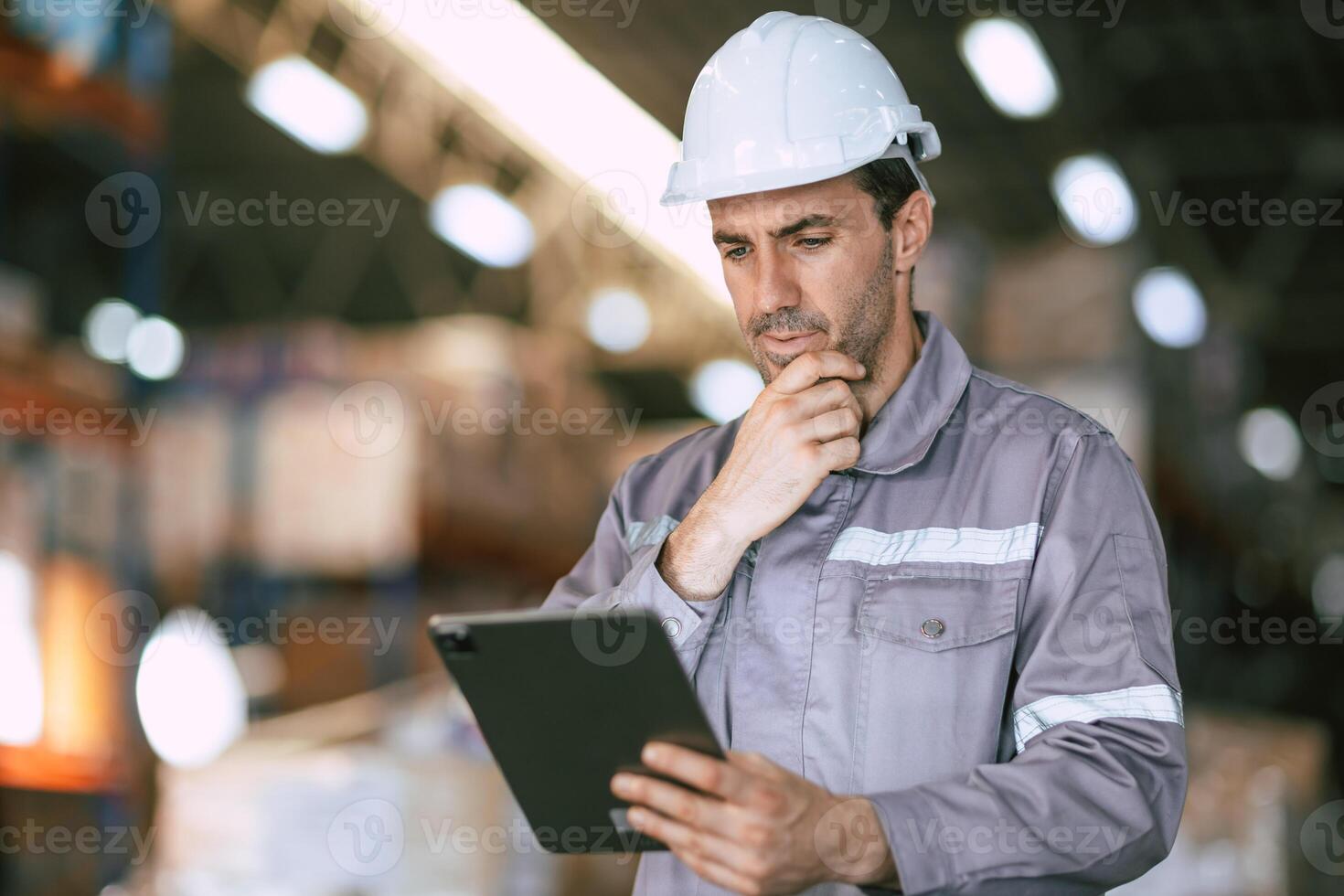 A man in a hard hat is holding a tablet photo