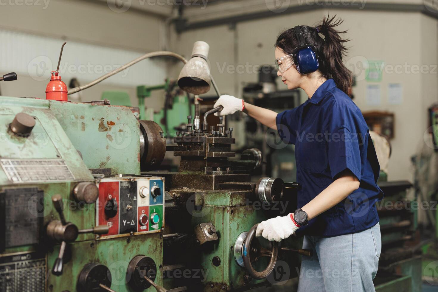 young engineer technician woman working with metal lathe machine in heavy industry factor photo