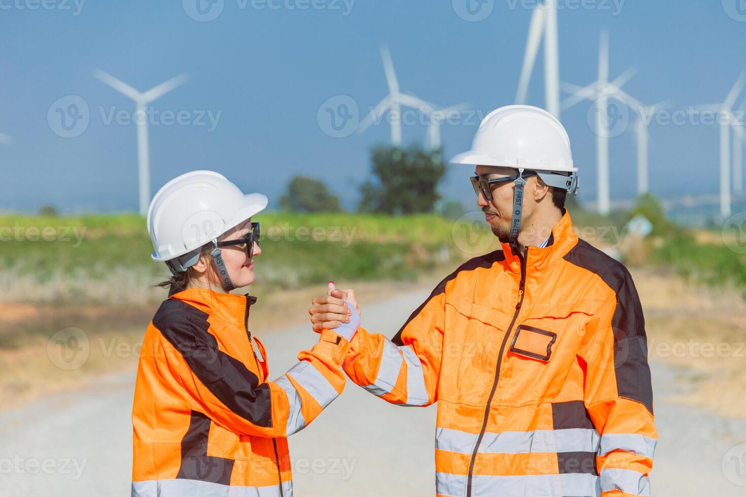 Two people in orange and white safety gear shaking hands photo