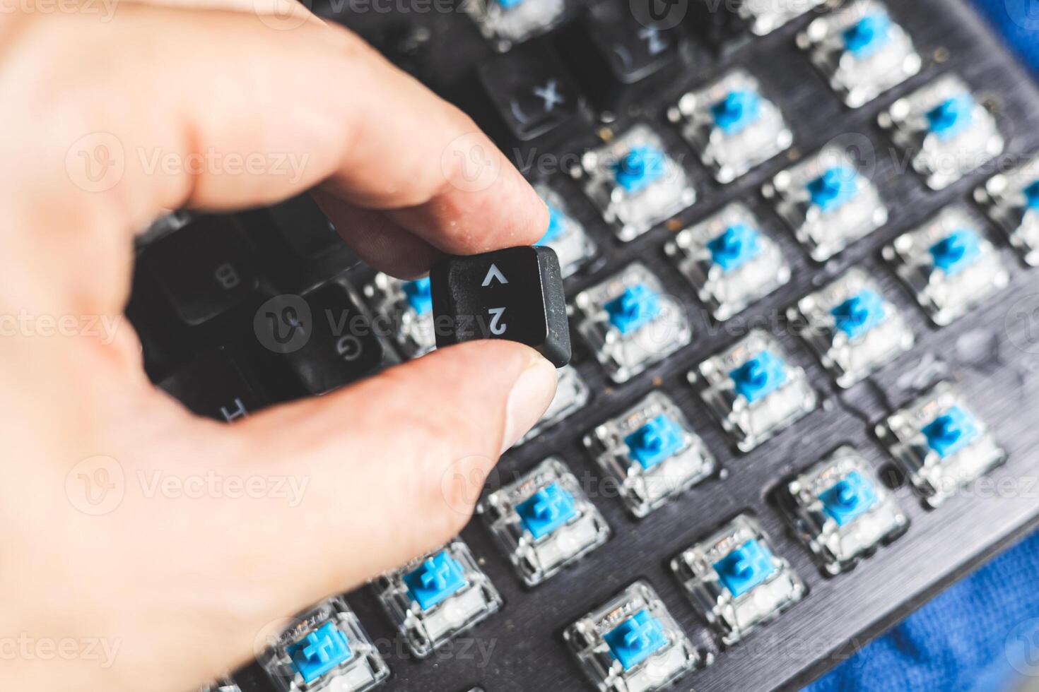 A person is holding a blue key on a keyboard photo