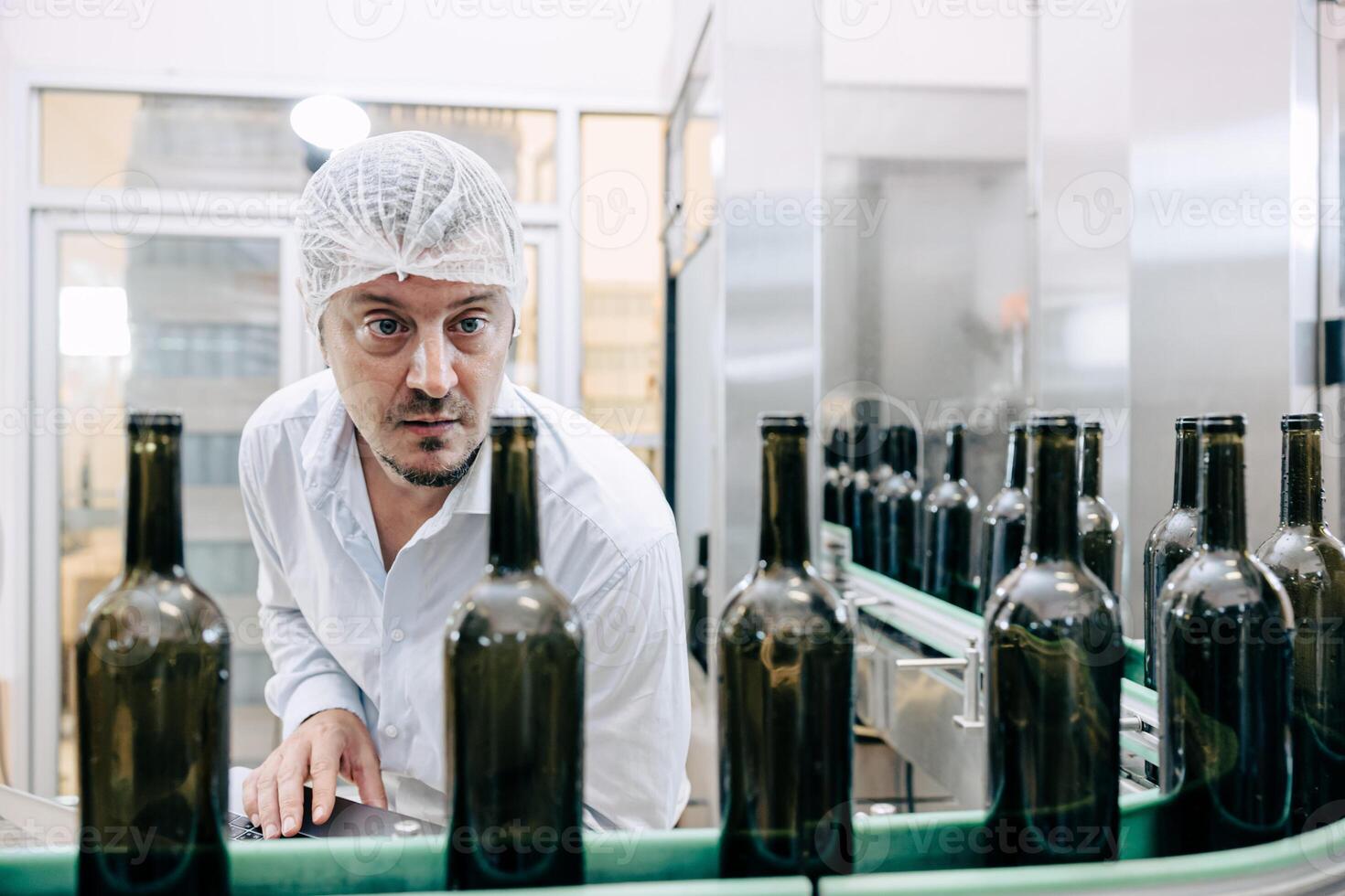 A man in a white hat is working on a conveyor belt photo
