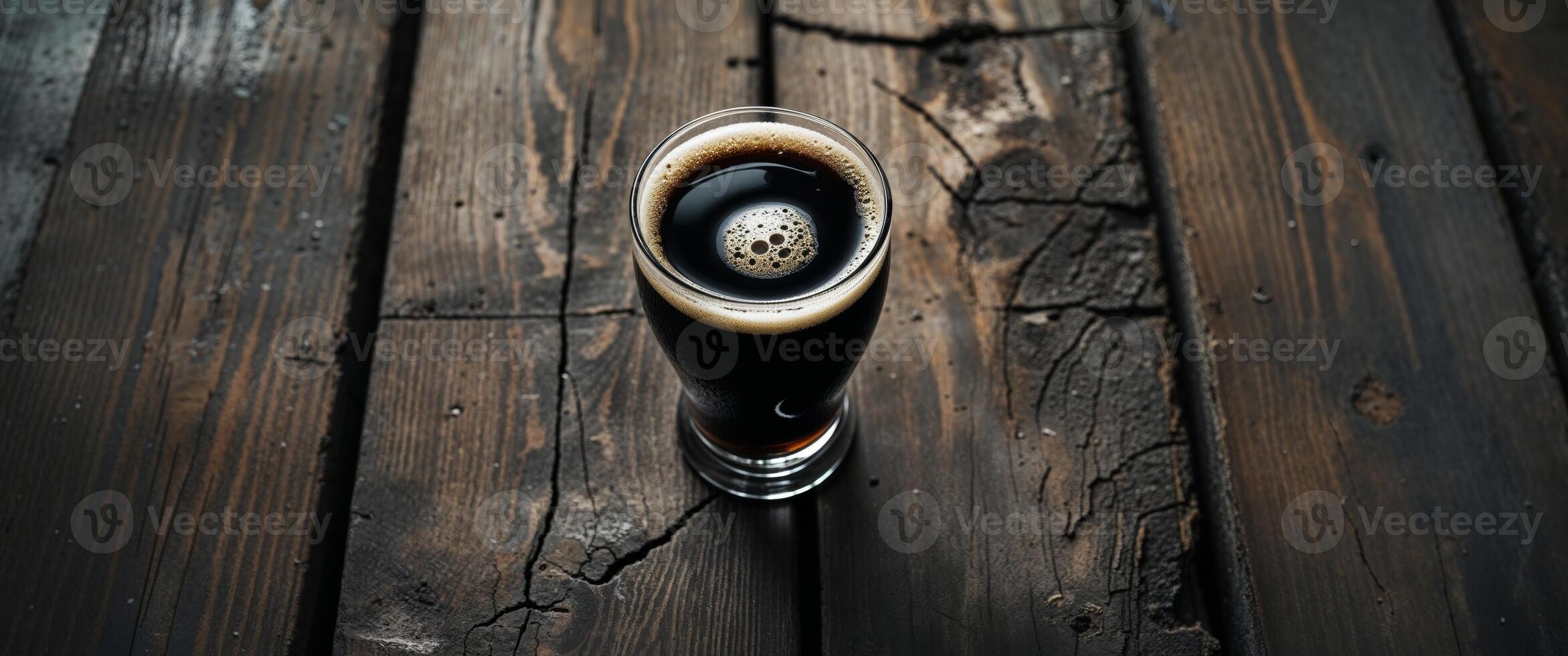 A pint of dark stout presented on weathered wooden planks background. photo