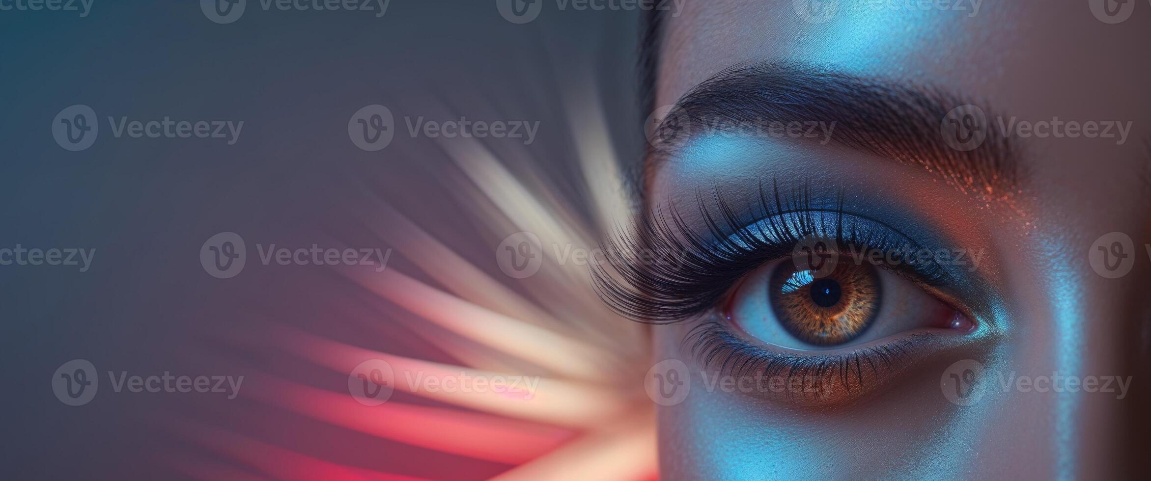 A tight shot of an eye with lengthy lashes and blue eyeshadow Red and blue lights cast in the backdrop. photo
