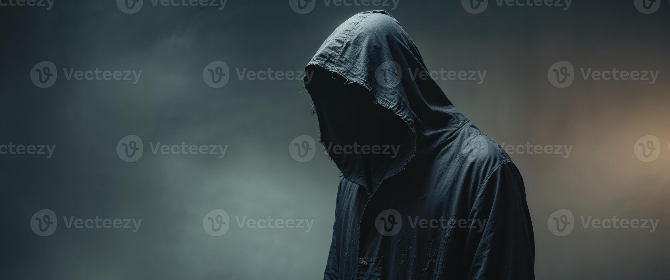 A man in a hooded robe standing in front of a dark background photo