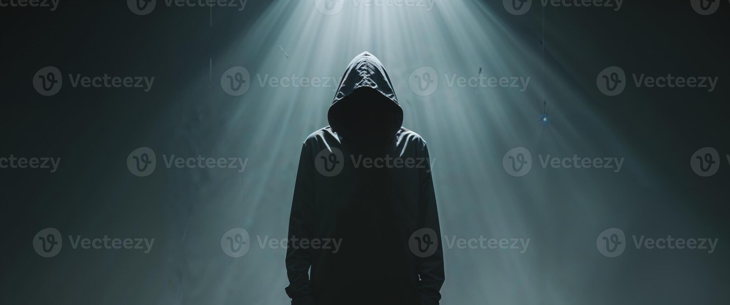 A person in a hooded robe standing in the dark photo