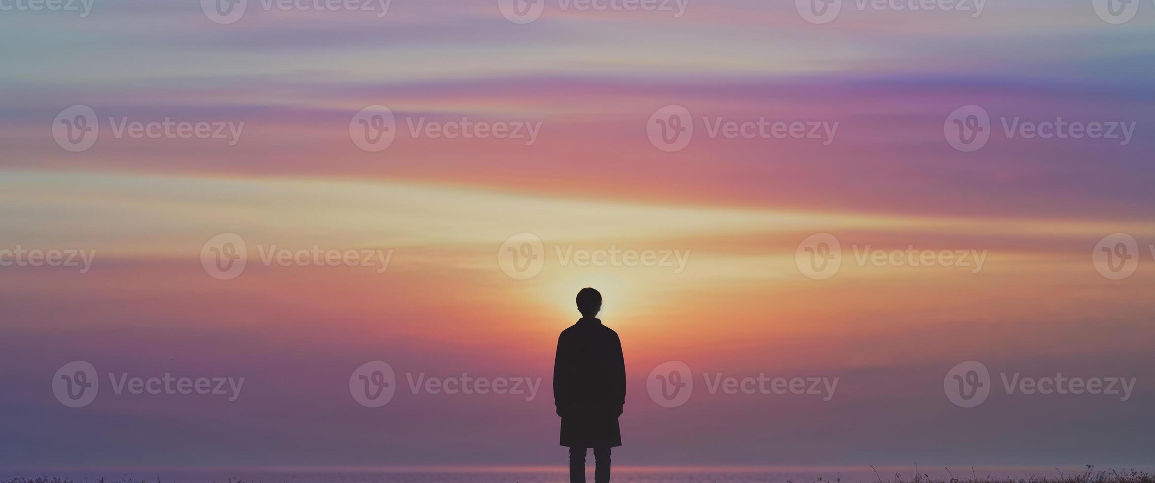 Silhouette of man standing on the beach at sunset photo