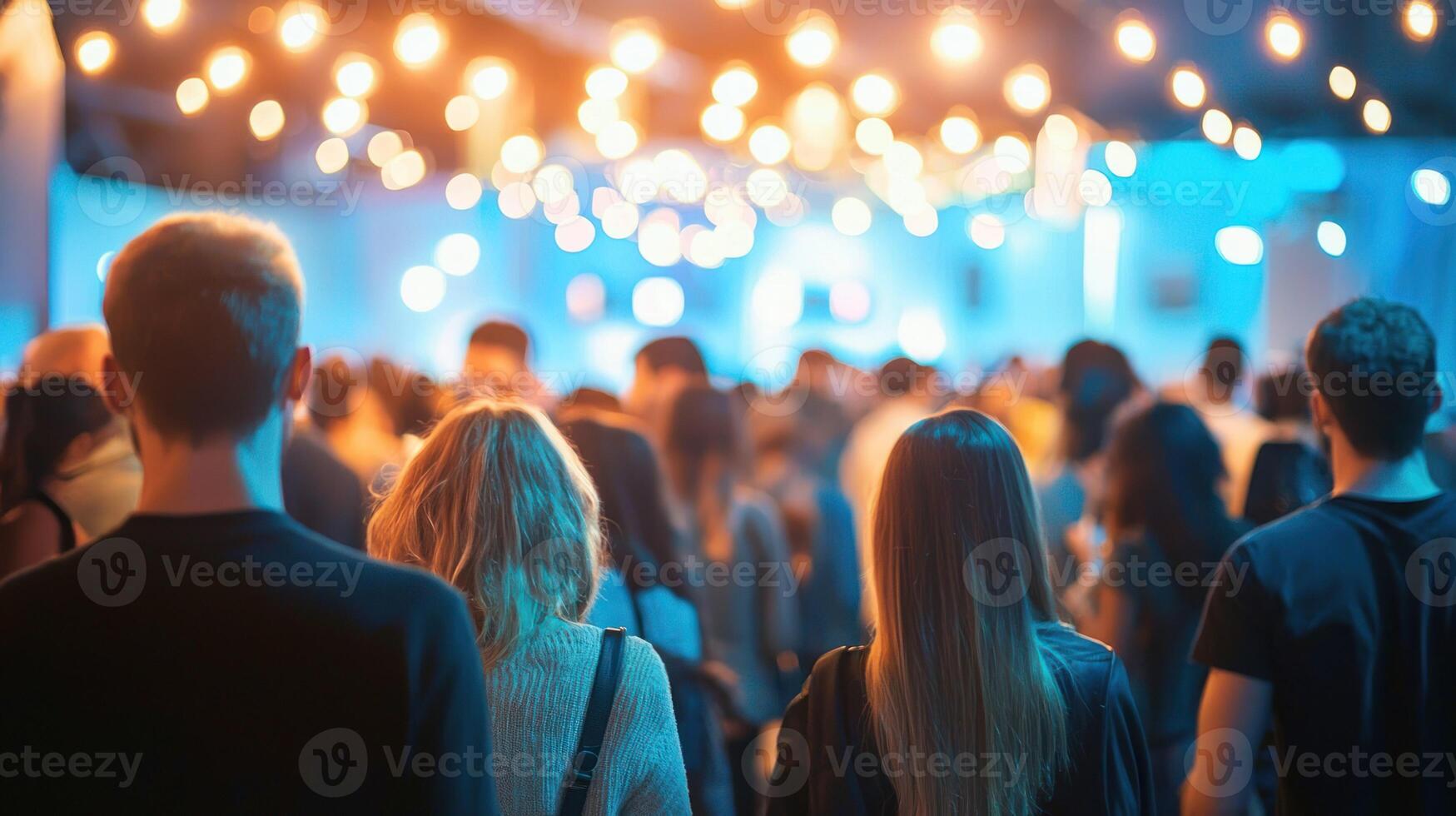 A group of people walking in a crowd, illuminated by string lights, with a blue and white color scheme. photo
