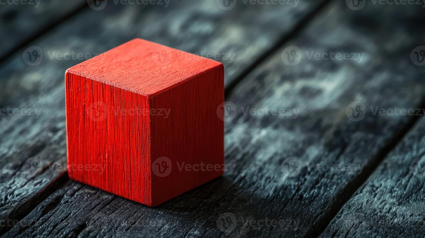 A red wooden block on a dark wooden surface with a blurred background. photo