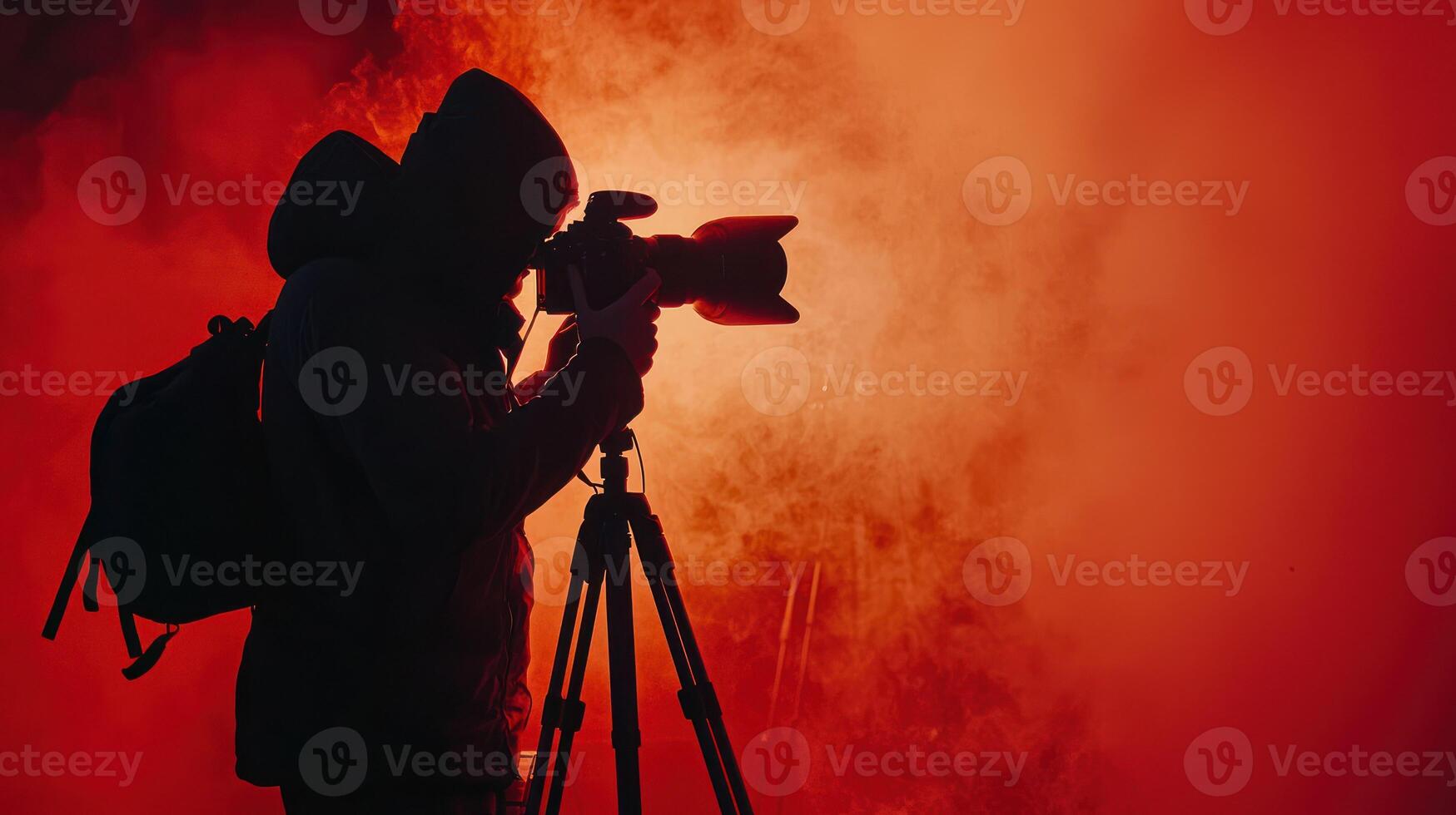 A photographer taking a picture in a foggy, red-lit environment. photo