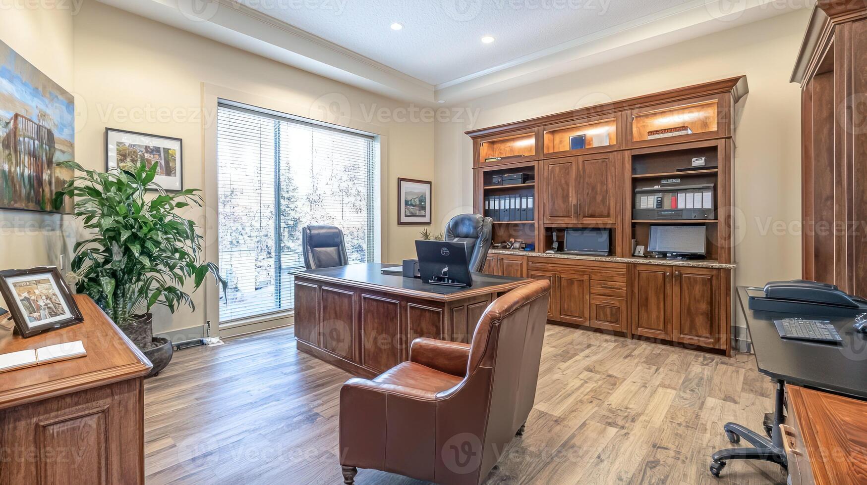 A spacious office with wooden furniture, a desk, chairs, and a large window overlooking a snowy landscape. photo