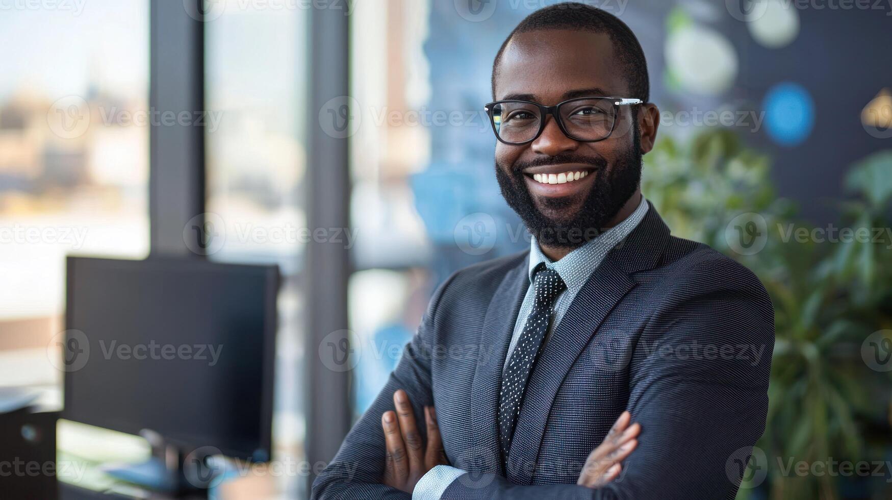 A smiling African American businessman wearing a suit and tie, standing in an office with a window in the background. photo