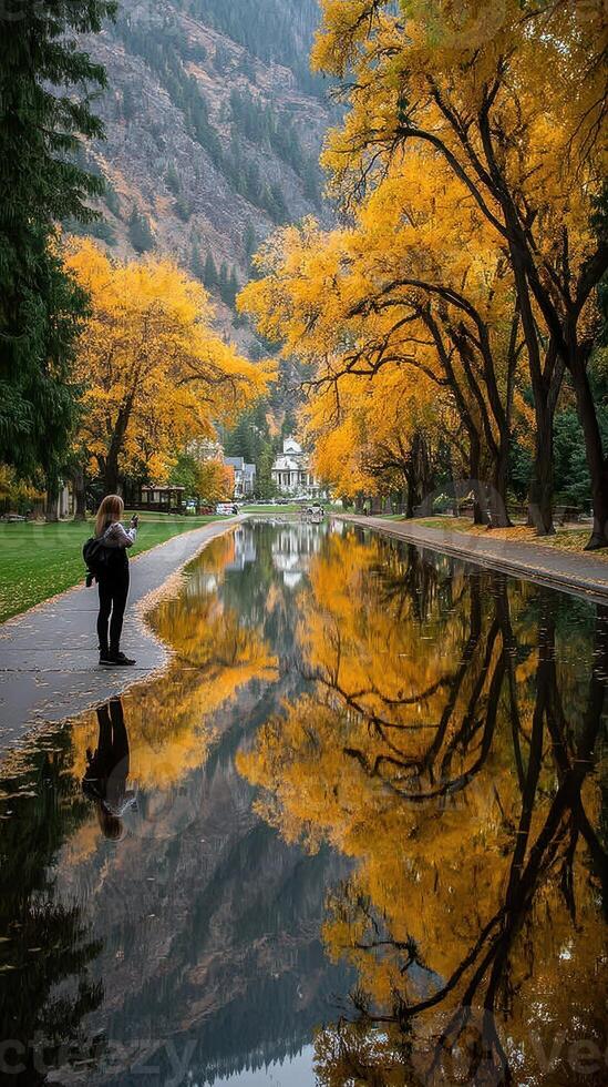 Stunning autumn reflections in a serene park setting with vibrant yellow trees beside a calm waterway photo