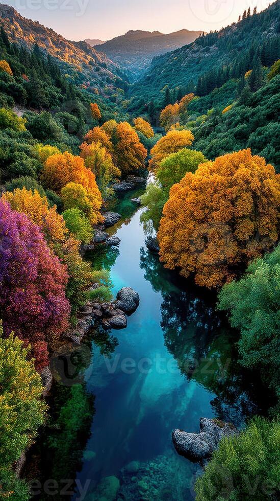 Colorful trees reflect in a serene river at sunset in a picturesque valley surrounded by mountains photo