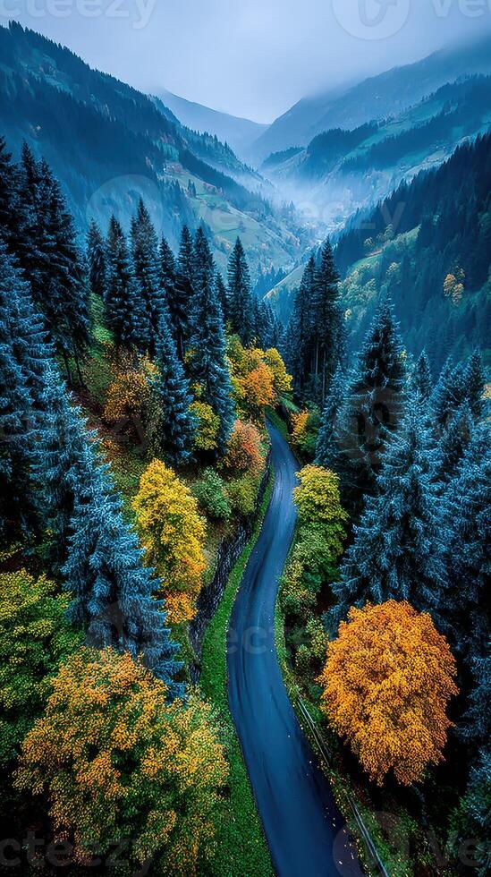 Breathtaking autumn view of a winding road amid vibrant foliage in a misty mountain landscape photo