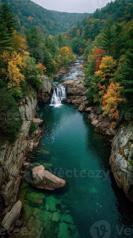 Autumn colors surround a serene waterfall and river in a mountainous landscape during the fall season photo