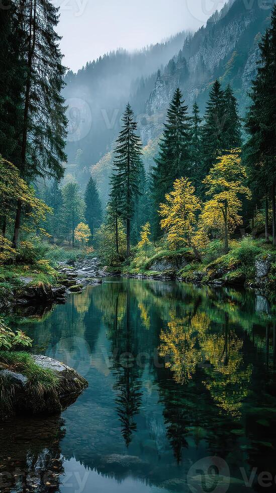Serene autumn landscape with golden trees reflecting in calm river surrounded by lush mountains photo