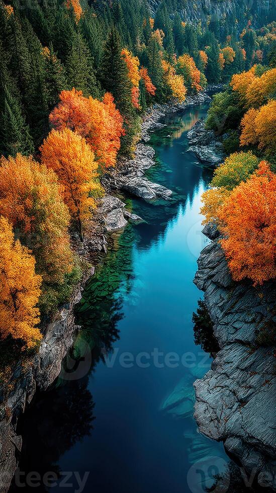 Beautiful autumn landscape with vibrant orange trees reflecting in a tranquil river surrounded by rocks and greenery photo
