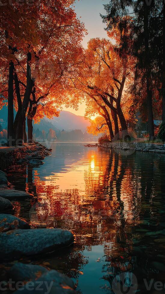 Vibrant autumn sunset reflecting on a calm lake surrounded by colorful trees photo