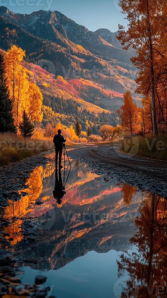 Photographer capturing autumn colors in a serene mountain landscape during golden hour photo
