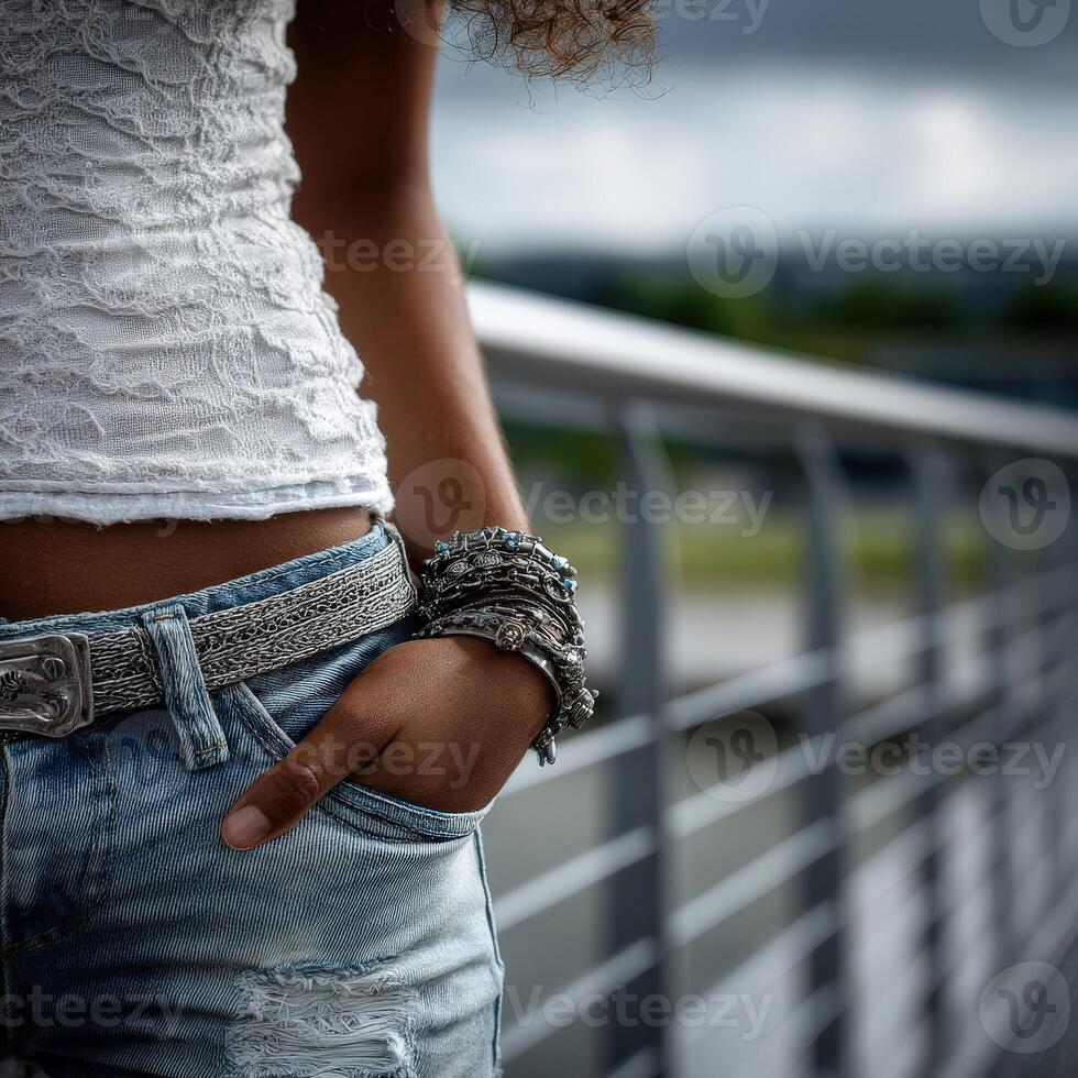 A person stands by a railing dressed in denim jeans and a fitted casual top photo
