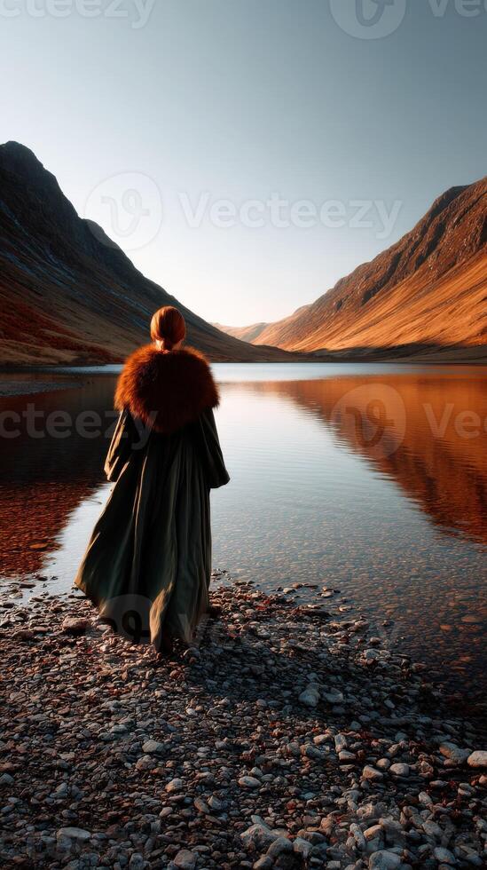 Viking woman standing by a tranquil lake amidst majestic mountains photo