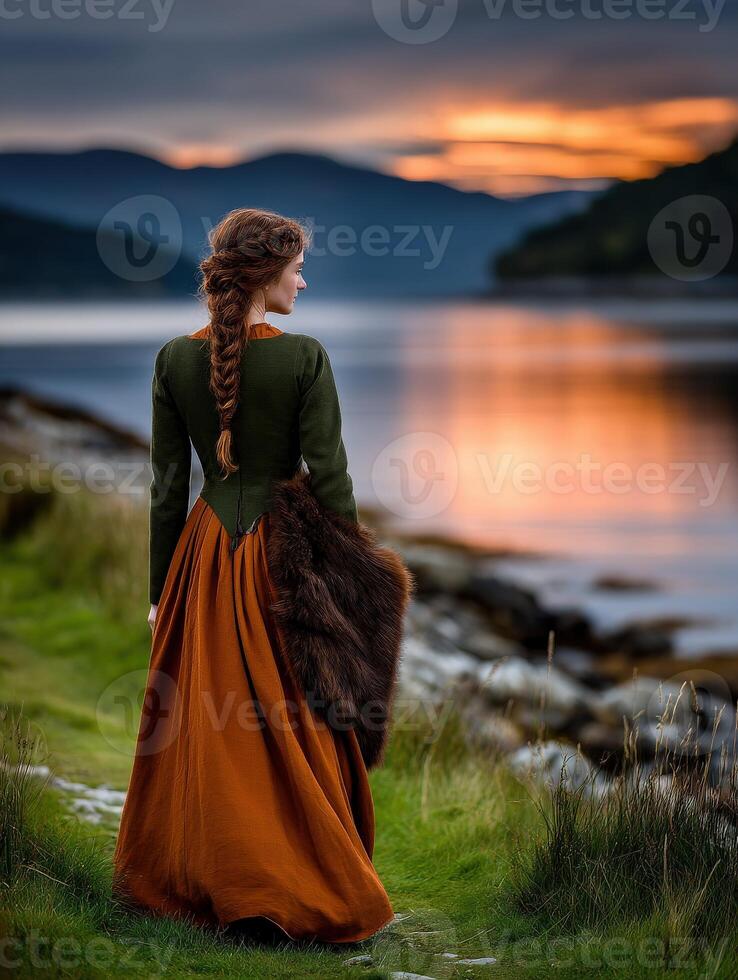Viking woman in traditional dress by the tranquil fjord at sunset photo