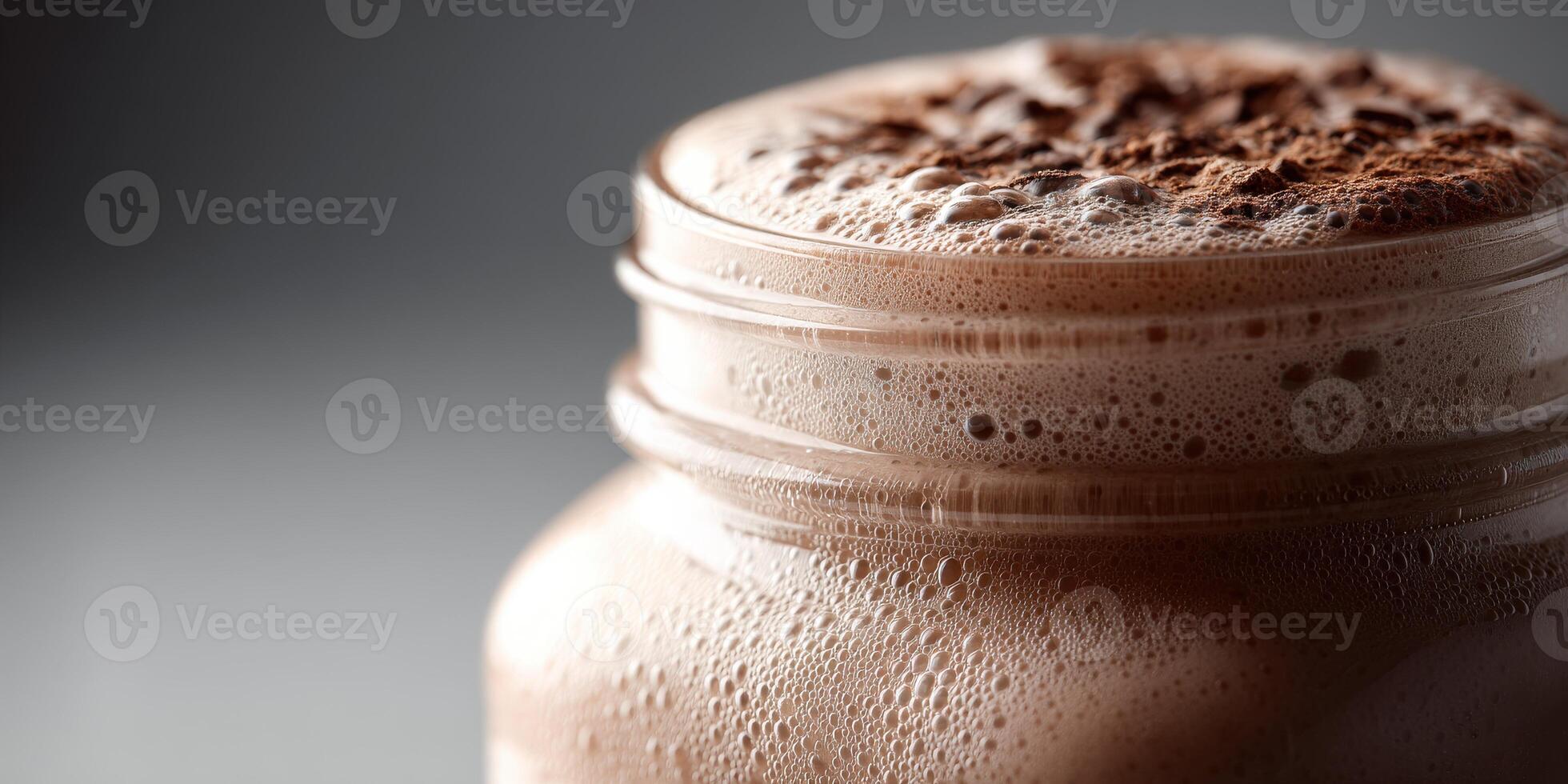 Protein shake topped with cocoa powder in a clear glass jar photo