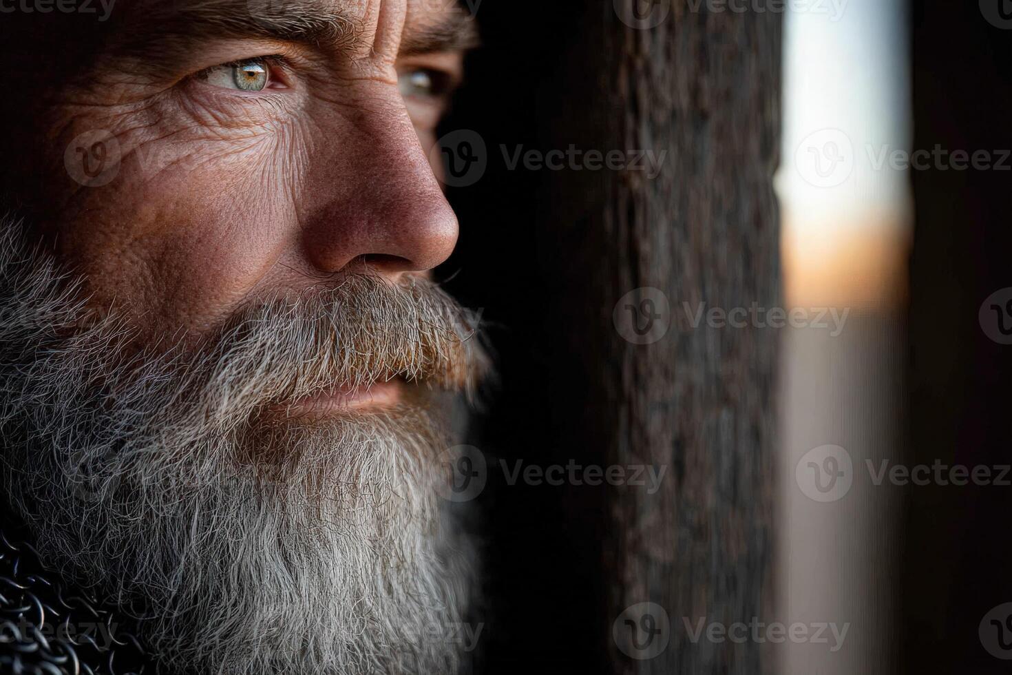 Man with a beard gazes thoughtfully out a window photo